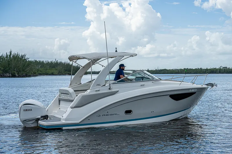 Slide: The Image of 2022 Regal 26 XO boat cruising on a calm lake under a cloudy sky. - 39