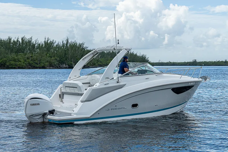 Slide: The Image of 2022 Regal 26 XO boat cruising on a calm lake with lush greenery. - 40