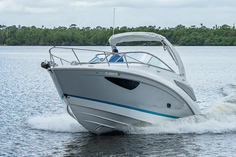 Slide: The Image of 2022 Regal 26 XO boat cruising on a lake with lush greenery in the background. - 47