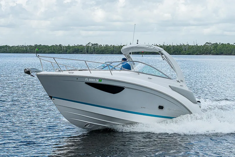 Slide: The Image of 2022 Regal 26 XO boat cruising on a lake under cloudy skies. - 48