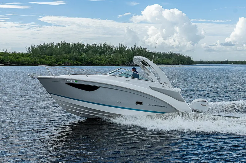 Slide: The Image of 2022 Regal 26 XO boat cruising on a scenic lake under a blue sky. - 49