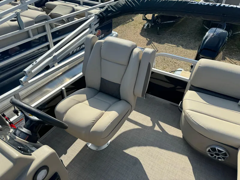 Slide: The Image of 2025 Sun Tracker Party Barge 16 DLX interior with beige seating and steering wheel. - 16