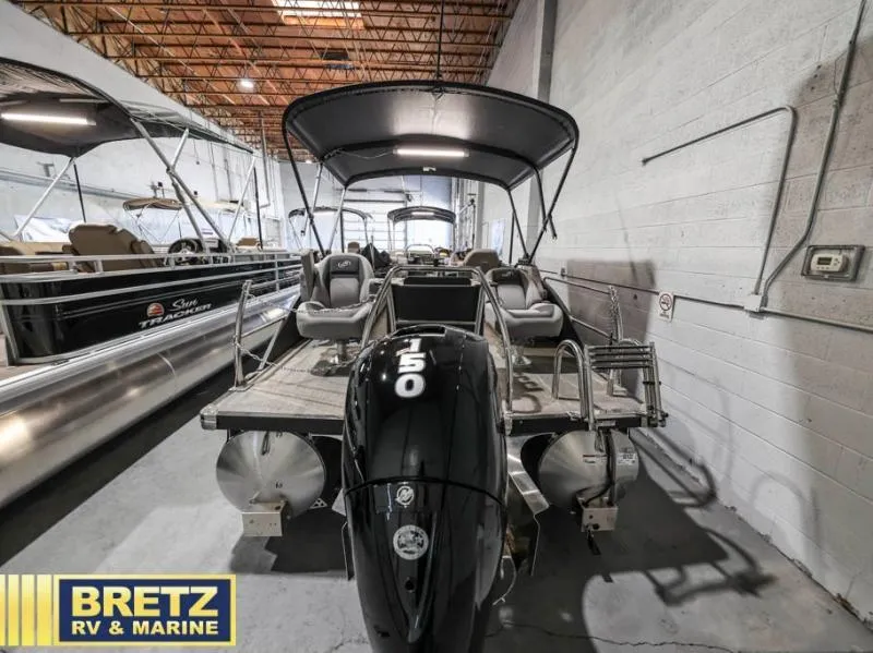 Slide: The Image of 2025 Aria Cast-N-Cruise A22CC pontoon boat in showroom, featuring powerful outboard motor. - 7