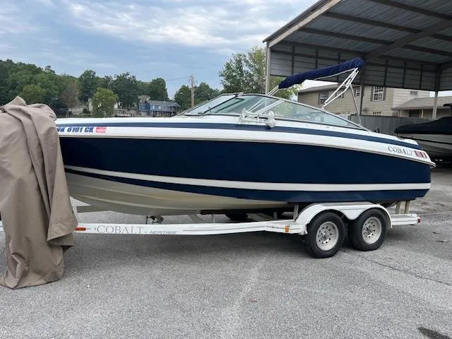 Slide: The Image of 1996 Cobalt 232 boat on trailer, parked outdoors under a cloudy sky. - 1