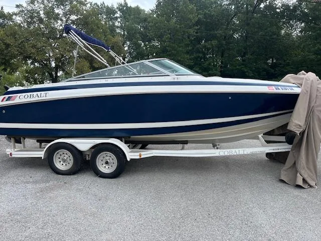 Slide: The Image of 1996 Cobalt 232 boat on trailer, blue and white, parked outdoors. - 2