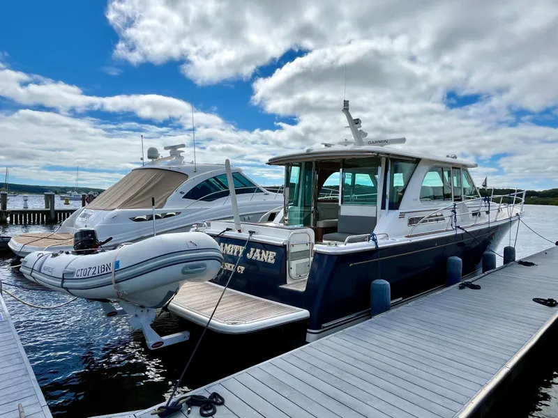Slide: The Image of 2018 Sabre 45 Salon Express yacht docked with inflatable boat, under cloudy sky. - 9