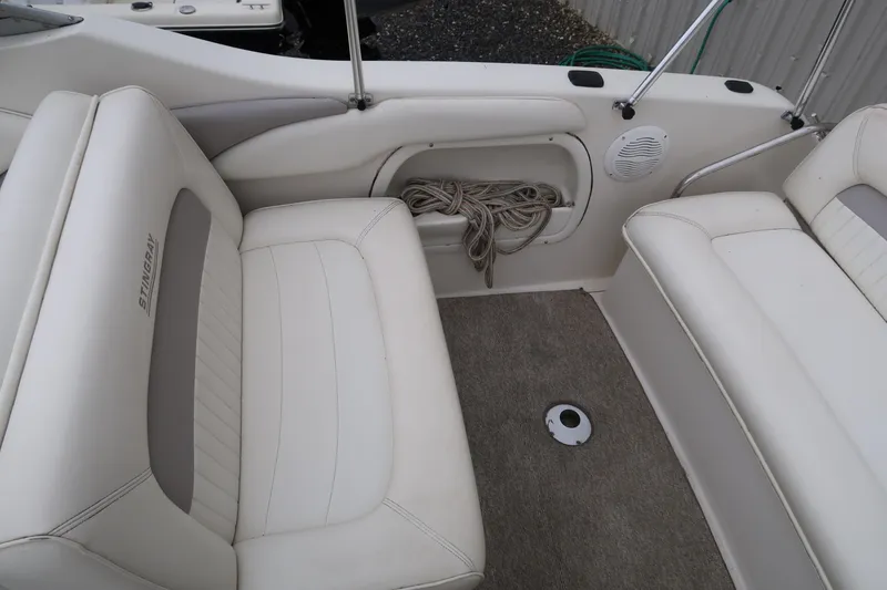 Slide: The Image of 2004 Stingray 240 CS boat interior with white seating and storage compartment. - 10