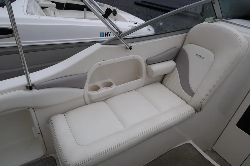 Slide: The Image of 2004 Stingray 240 CS boat interior with white seating and cup holders. - 11