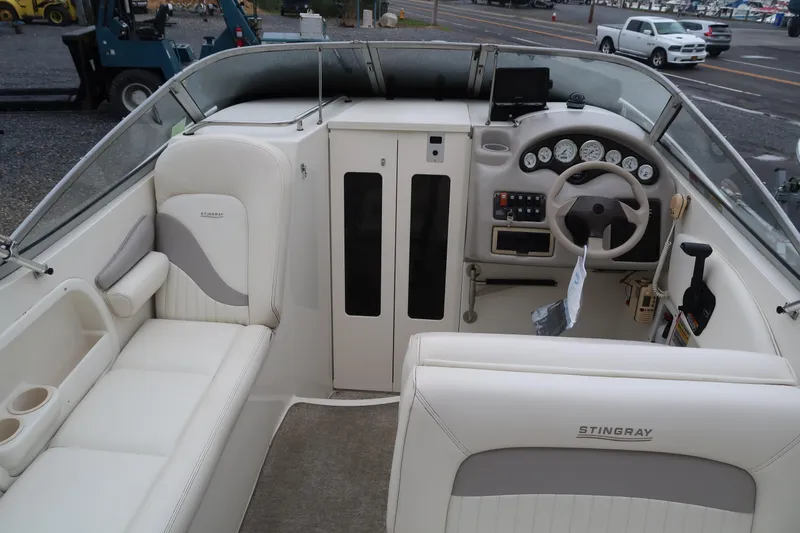 Slide: The Image of 2004 Stingray 240 CS boat interior with white seating and control panel. - 12