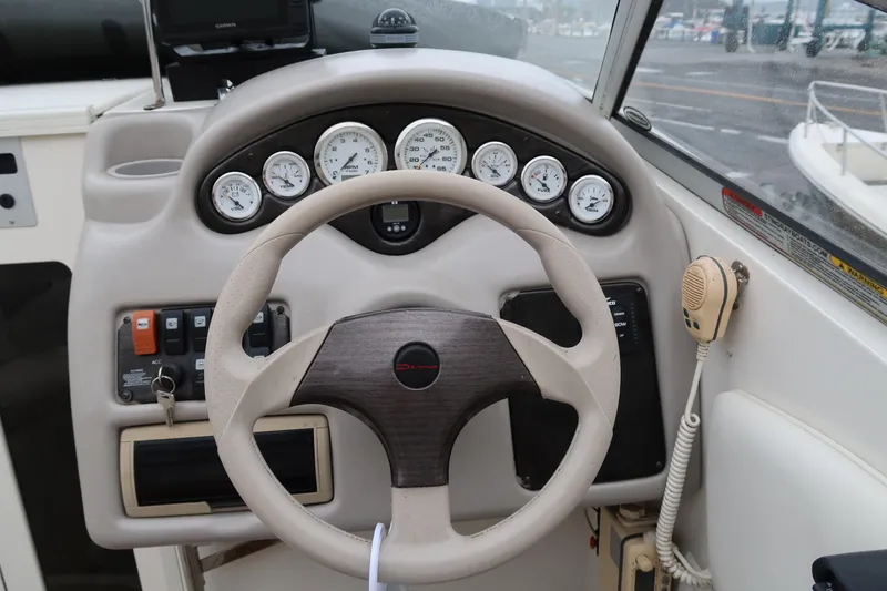 Slide: The Image of Steering wheel and dashboard of a 2004 Stingray 240 CS boat with gauges and controls. - 14