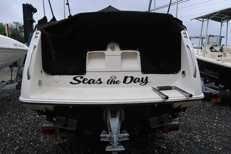 Slide: The Image of 2004 Stingray 240 CS boat with "Seas the Day" text on the stern, parked on gravel. - 2
