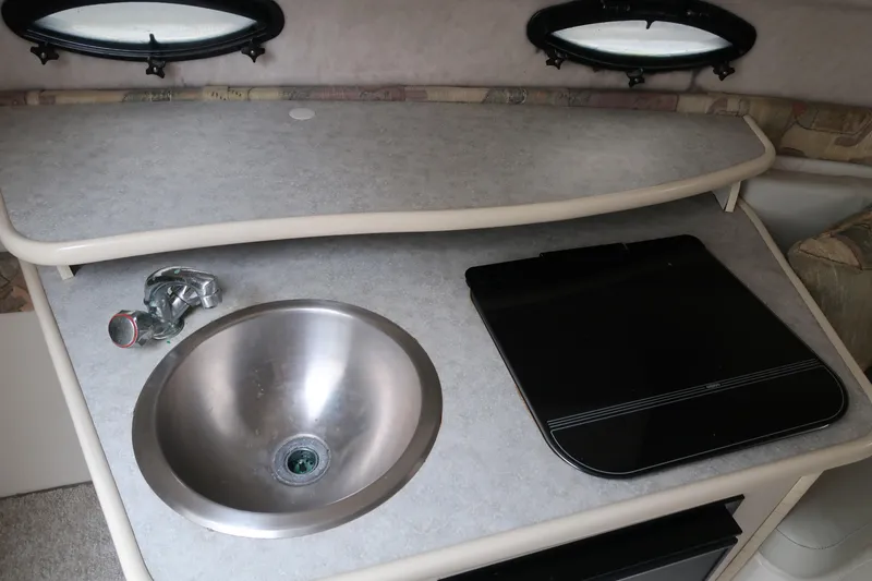 Slide: The Image of 2004 Stingray 240 CS boat interior with sink and stove in compact kitchen area. - 23