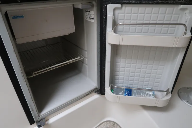 Slide: The Image of Open mini fridge in a 2004 Stingray 240 CS boat, with a water bottle inside the door. - 24