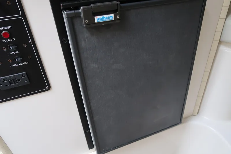 Slide: The Image of 2004 Stingray 240 CS boat interior with a compact refrigerator and control panel. - 25