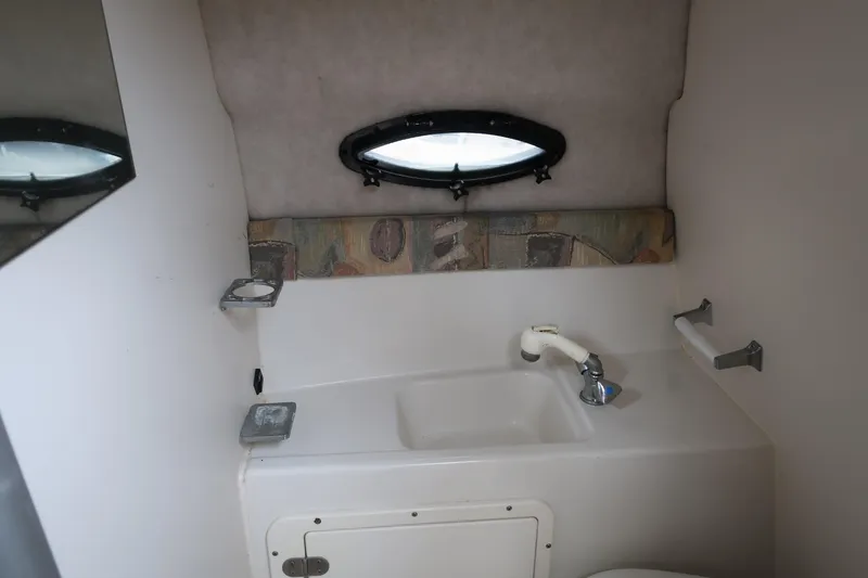 Slide: The Image of 2004 Stingray 240 CS boat interior with sink and porthole window. - 29