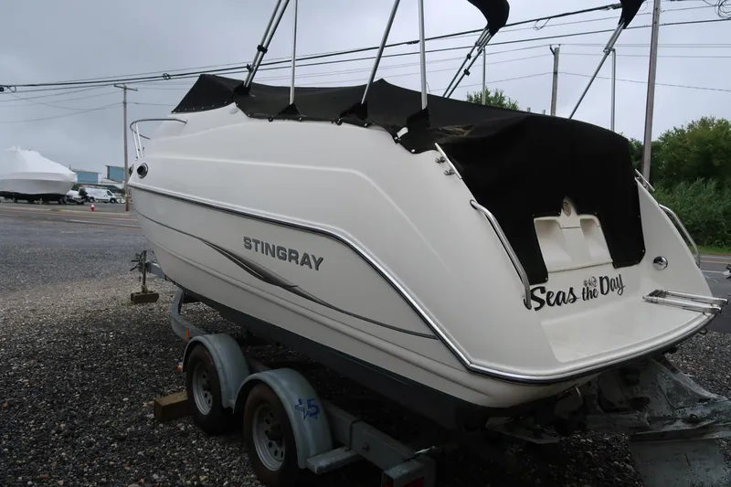 Slide: The Image of 2004 Stingray 240 CS boat on trailer, covered, parked outdoors. - 3