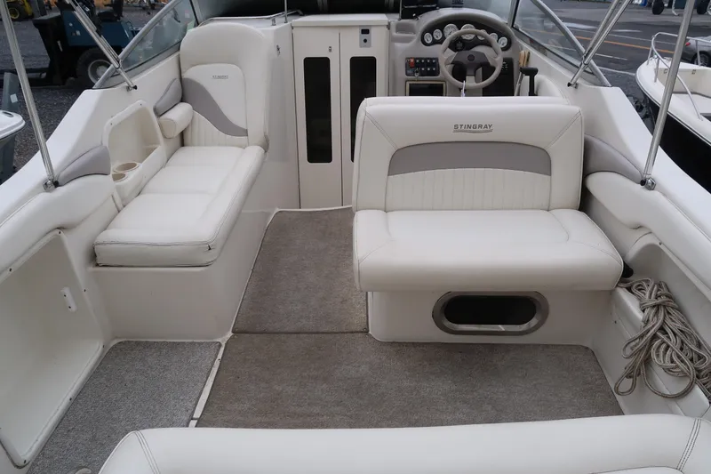 Slide: The Image of 2004 Stingray 240 CS boat interior with white seating and steering wheel. - 8
