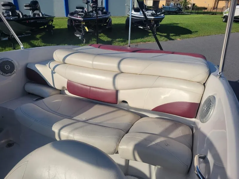 Slide: The Image of 2011 Tahoe Q5i boat interior with beige and maroon seating, parked outdoors. - 9