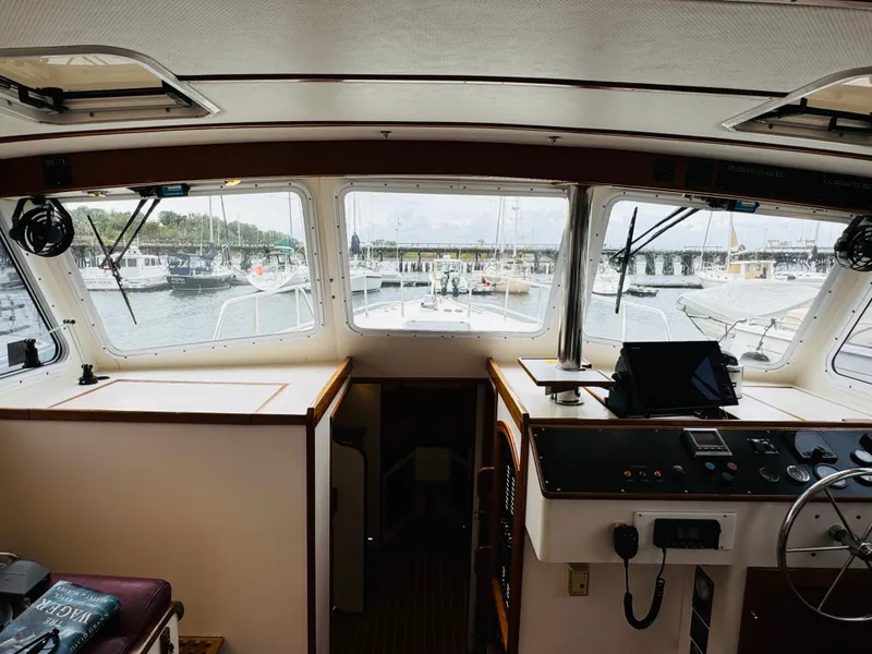 Slide: The Image of Interior view of 2000 Holland 38 Downeast Cruiser, showcasing helm and marina through windows. - 12