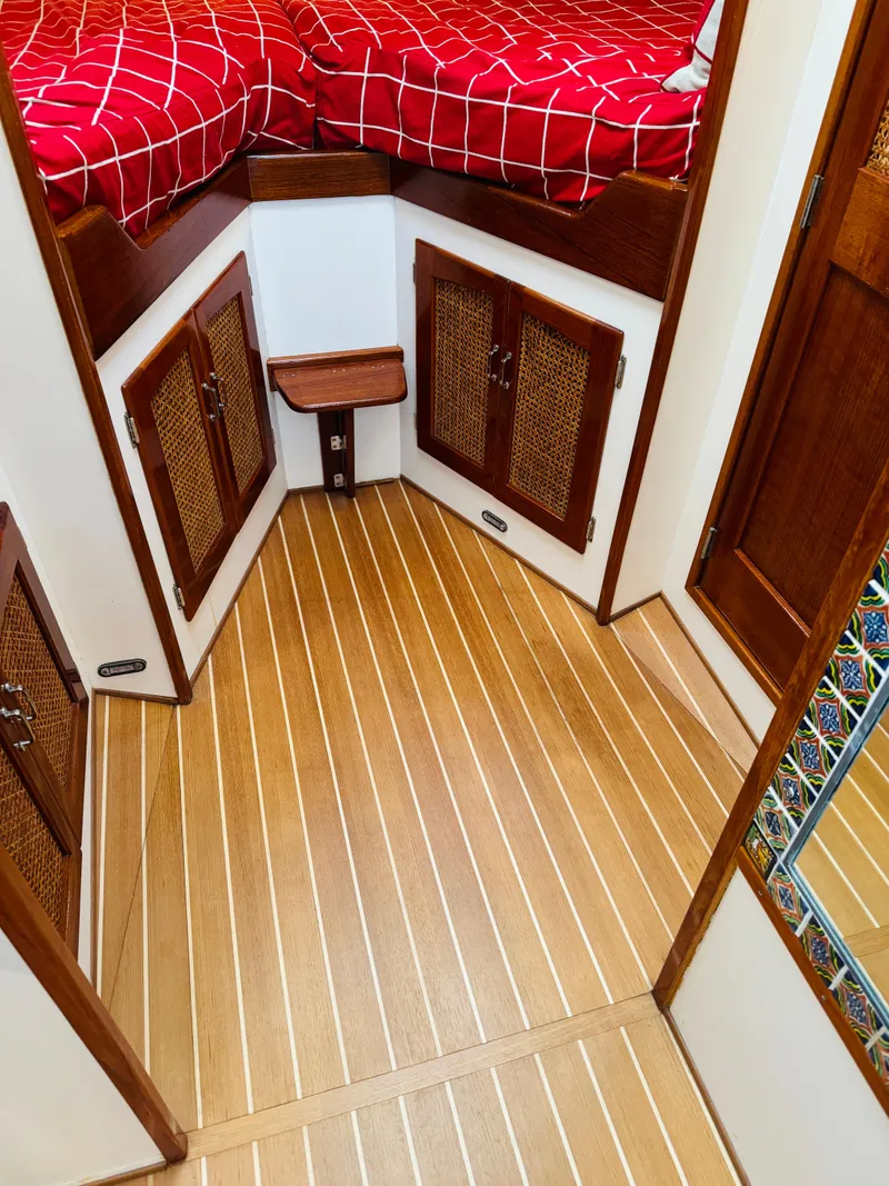 Slide: The Image of Interior of 2000 Holland 38 Downeast Cruiser with wood flooring and red bedding. - 20
