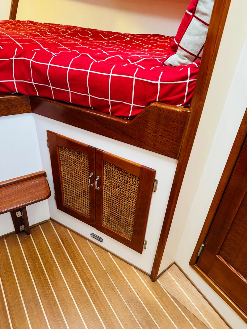 Slide: The Image of Holland 38 Downeast Cruiser 2000 interior with red bedding and wooden cabinetry. - 21