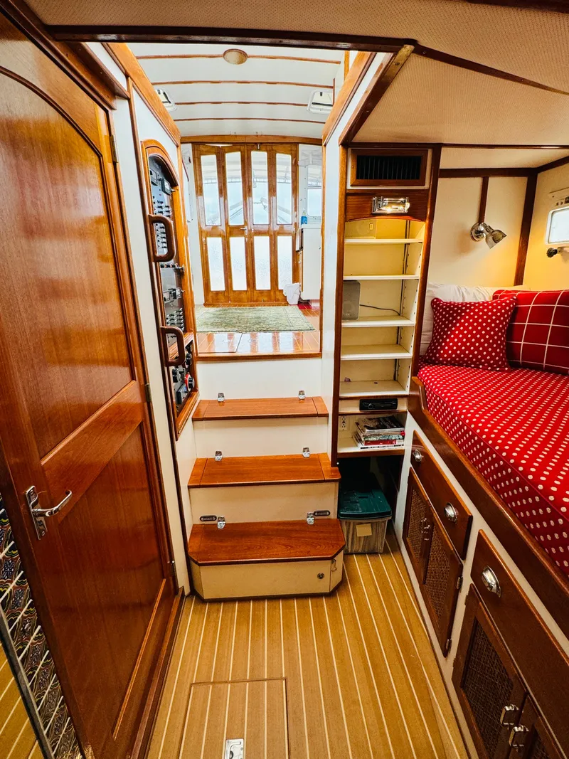 Slide: The Image of Interior of 2000 Holland 38 Downeast Cruiser with wooden finishes and cozy red bedding. - 27