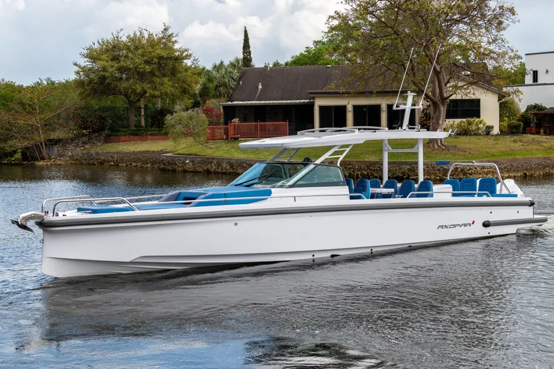 Slide: The Image of 2024 Axopar 37 Sun Top boat cruising on a calm river near a house. - 1