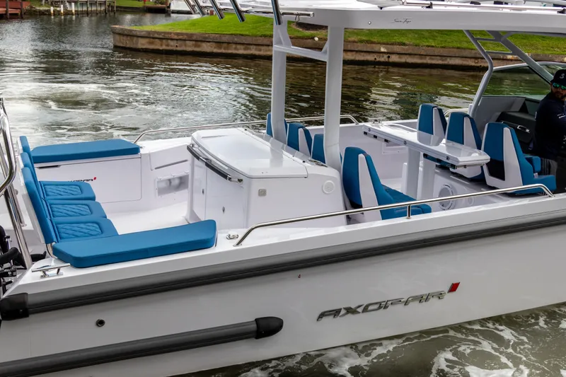 Slide: The Image of 2024 Axopar 37 Sun Top boat with blue seating, cruising on water. - 5