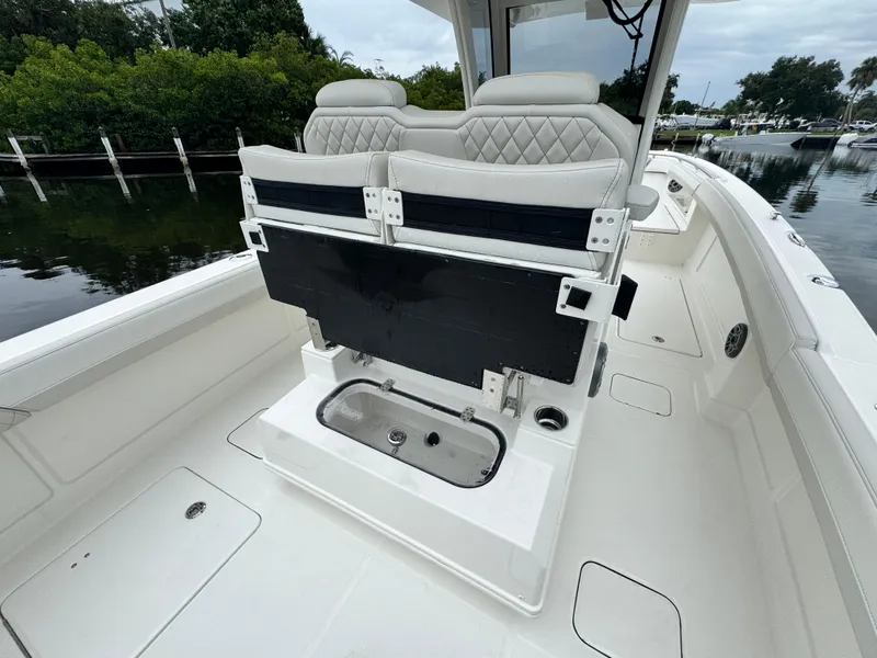 Slide: The Image of 2025 World Cat 280 CC-X boat interior with seating and storage, docked near lush greenery. - 13