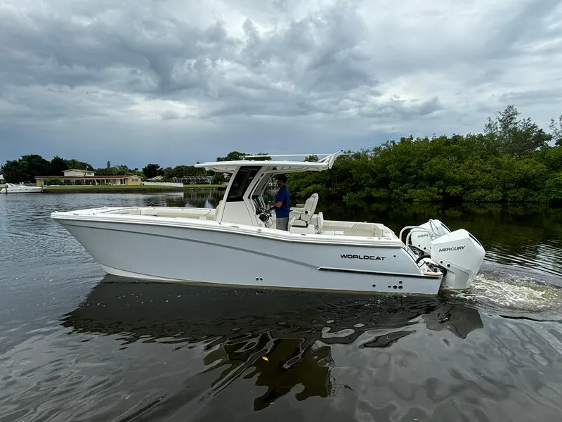 Slide: The Image of 2025 World Cat 280 CC-X boat cruising on a calm river under cloudy skies. - 2