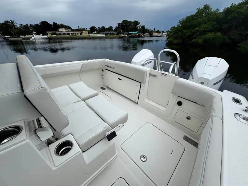 Slide: The Image of 2025 World Cat 280 CC-X boat interior with seating and storage, docked on a calm waterway. - 8
