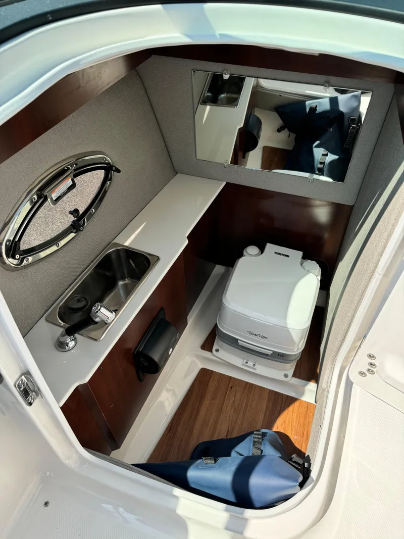 Slide: The Image of 2025 Chaparral 287 SSX boat interior with sink, mirror, and portable toilet. - 12