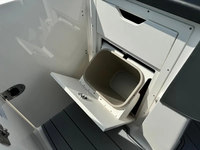 Slide: The Image of 2025 Chaparral 287 SSX boat interior with open storage compartment and trash bin. - 15