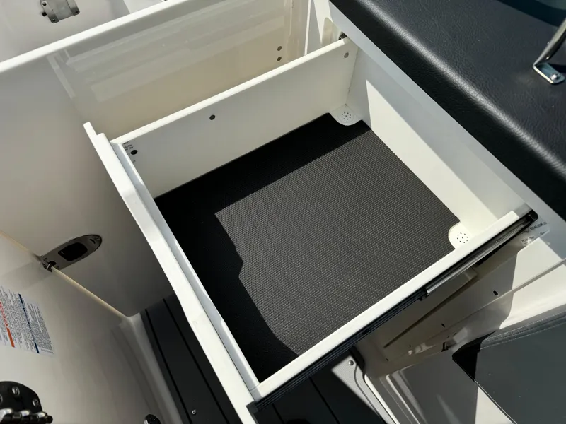 Slide: The Image of 2025 Chaparral 287 SSX boat storage compartment with black mat interior. - 16