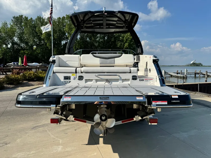 Slide: The Image of 2025 Chaparral 287 SSX boat with spacious swim platform, docked by a scenic waterfront. - 2