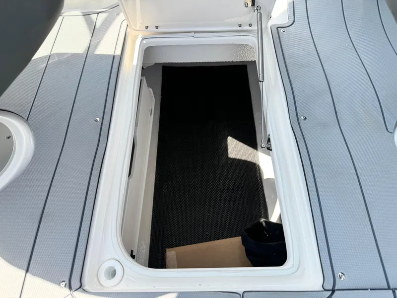 Slide: The Image of 2025 Chaparral 287 SSX boat storage compartment with open hatch and textured flooring. - 30
