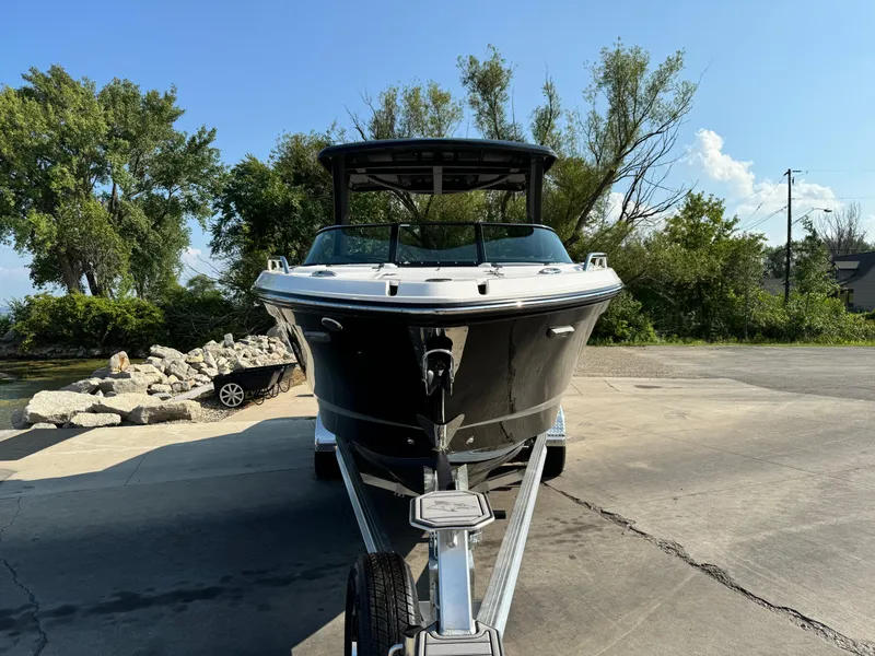 Slide: The Image of 2025 Chaparral 287 SSX boat on trailer, parked outdoors, surrounded by trees. - 6