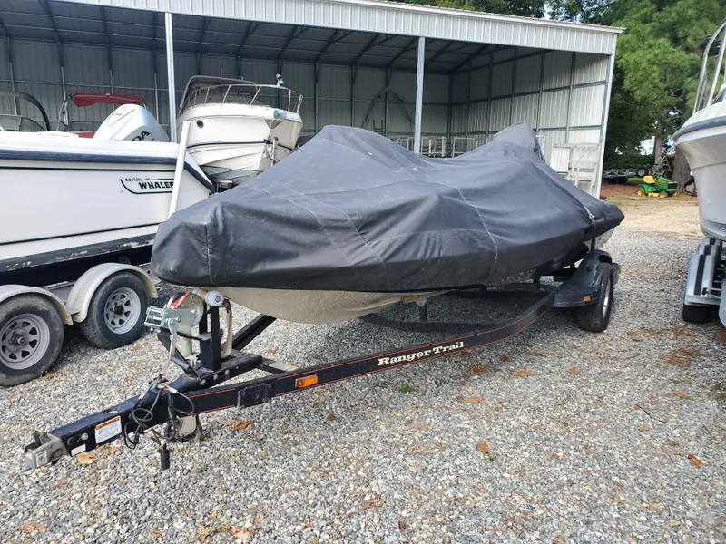 Slide: The Image of 2003 Ranger 185 VX/VS boat covered, on trailer, parked in gravel lot near other boats. - 5
