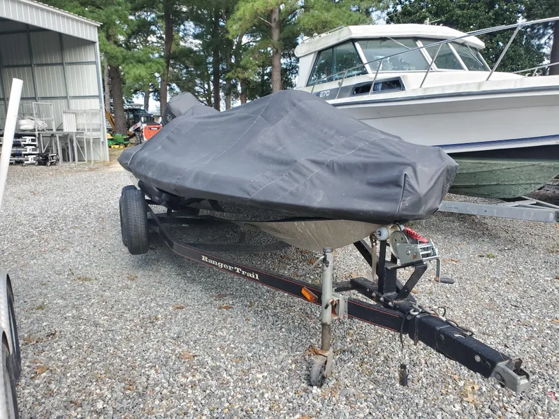 Slide: The Image of 2003 Ranger 185 VX/VS boat covered on trailer, parked outdoors near other boats. - 6