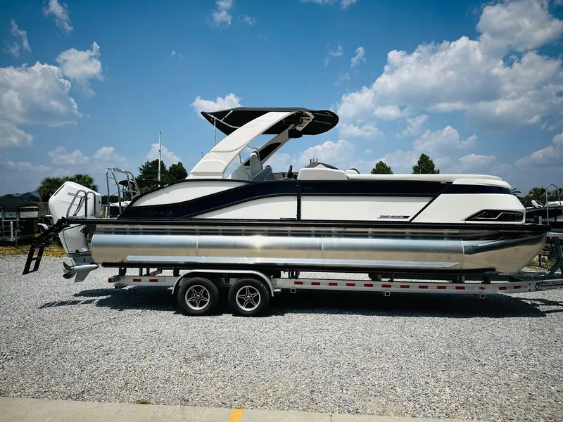 Slide: The Image of 2025 Harris Grand Mariner 250 pontoon boat on trailer under blue sky. - 1