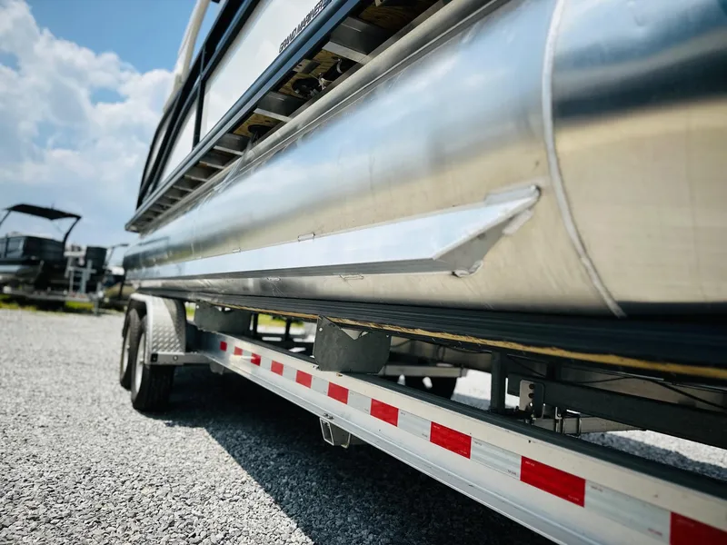 Slide: The Image of 2025 Harris Grand Mariner 250 pontoon boat on a trailer, sunny day, gravel surface. - 10