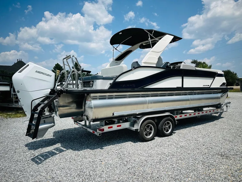 Slide: The Image of 2025 Harris Grand Mariner 250 pontoon boat on trailer, under clear blue sky. - 2