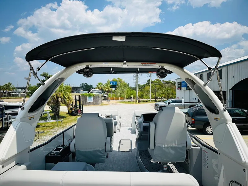 Slide: The Image of 2025 Harris Grand Mariner 250 boat interior with canopy, parked outdoors under a blue sky. - 24