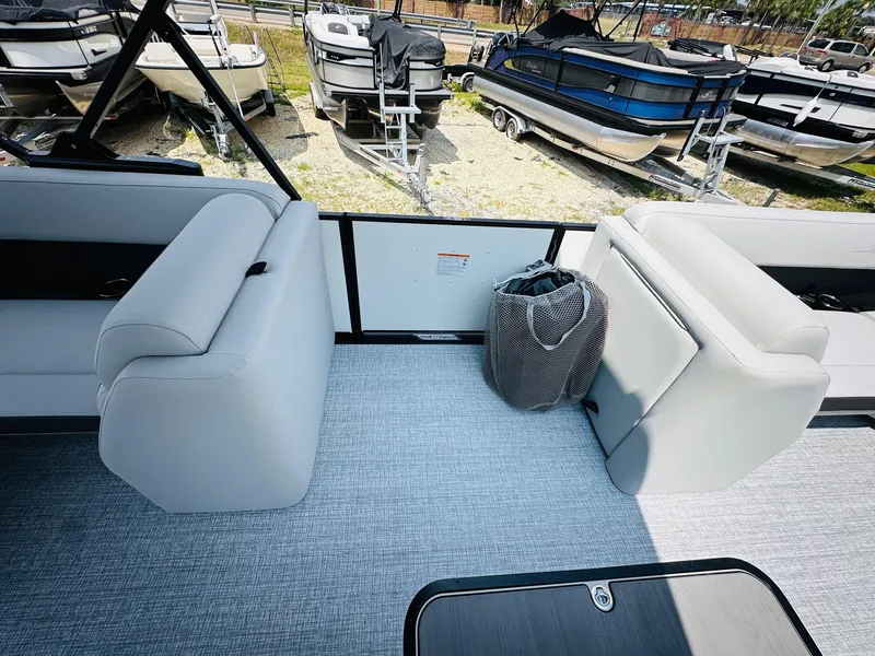 Slide: The Image of 2025 Harris Cruiser 230 pontoon boat interior with gray seating and carpet, docked among other boats. - 13