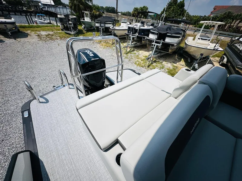 Slide: The Image of 2025 Harris Cruiser 230 pontoon boat with outboard motor, docked among other boats. - 16