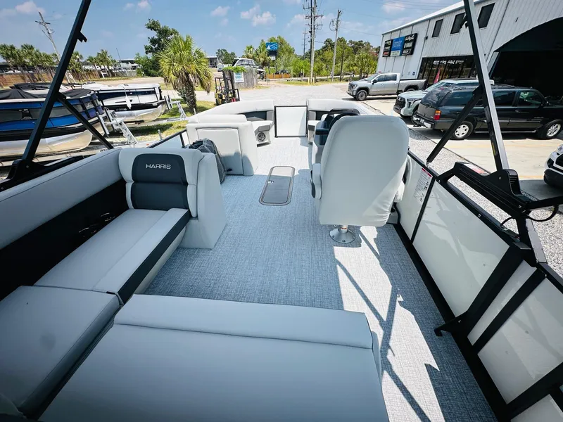 Slide: The Image of 2025 Harris Cruiser 230 boat interior with modern seating and steering, parked outdoors. - 18