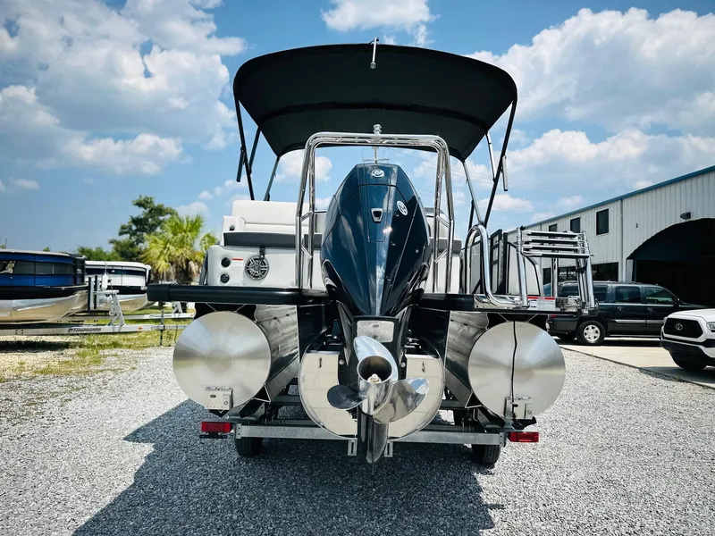 Slide: The Image of 2025 Harris Cruiser 230 pontoon boat, rear view, parked outdoors under a blue sky. - 3
