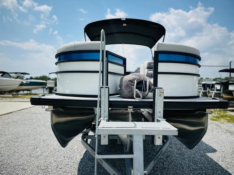 Slide: The Image of 2025 Harris Cruiser 230 pontoon boat on trailer under a sunny sky. - 8
