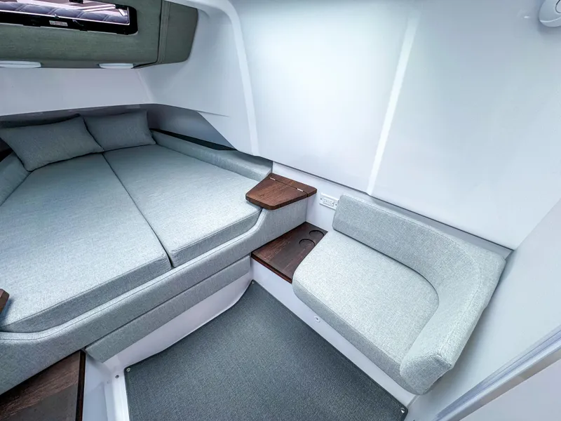 Slide: The Image of 2024 Axopar 37XC CROSS CABIN interior with modern seating and cozy sleeping area. - 13