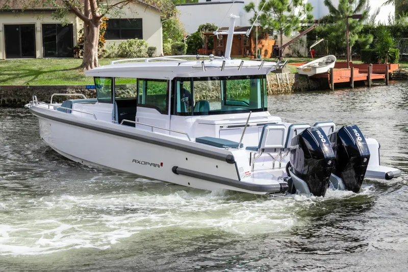 Slide: The Image of 2024 Axopar 37XC CROSS CABIN boat cruising on a river with dual outboard engines. - 2